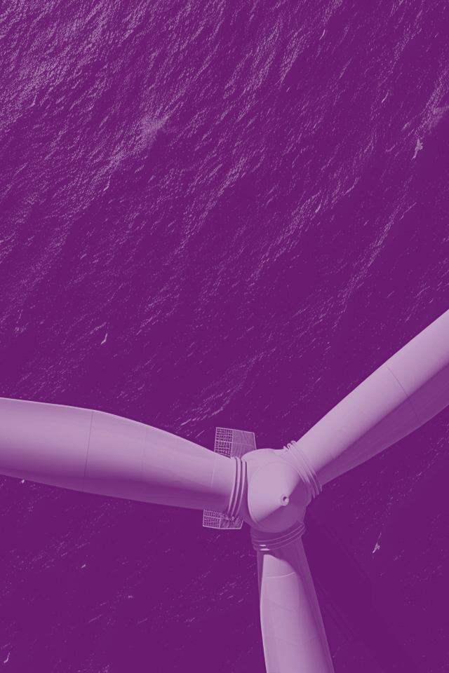 Aerial view of white offshore wind turbine hub and blades from above, showing the three-blade rotor assembly against dark blue ocean water with visible wave patterns