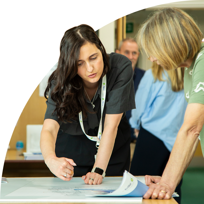 Woman pointing at a document on a table while discussing with colleagues